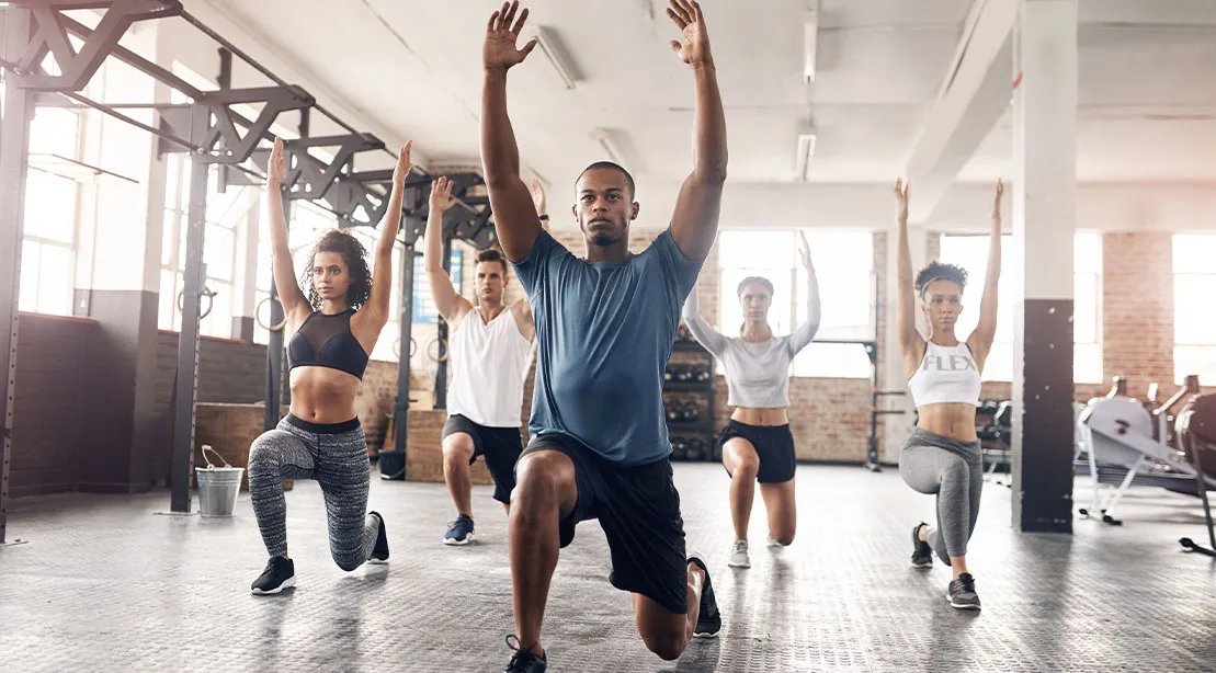 Fit athletic man leading a group fitness class in warmups