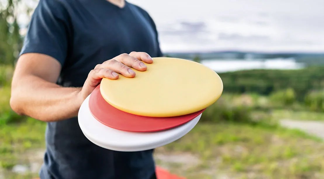 Disc Golfer holding various colored disc for disc golf