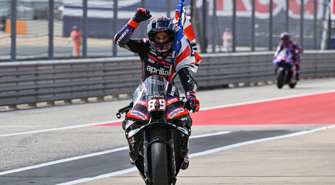 MotoGP racer and champion Jorge Martin on his bike raising his arm in victory after becoming a MotoGP champion