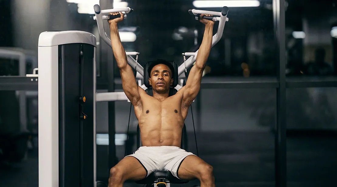 Fit athletic man performing a Seated Shoulder Press using a machine