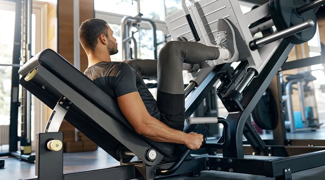Fit athletic man performing beginner leg presses for a building muscles